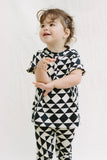  An image of a small child with short dark hair who is wearing black and white tri-print Leggins and t-shirt matching set in the Rosa Bloom tri-print design.