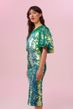 Side view of a dark haired woman wearing a Rosa Bloom green sequin mid length sequin tube skirt