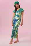 A woman with long hair, facing the viewer wearing an iridescent pale green sequin long dress. A figure hugging  dress down to the ankles with small capped sleeves completely covered in large round holographic Rosa Bloom sequins. The sequin colours shine in the studio lights, creating a mix of shimmering colours of sage green, mint and a warm peachy gold making this sequin dress glow when worn. The model is also wearing a matching sequinned beret hat.