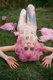 Pink haired girl lying down in green grass at a festival wearing sunglasses, many pink items of clothing and Rosa Bloom White Opal Sequin Indus Leggings