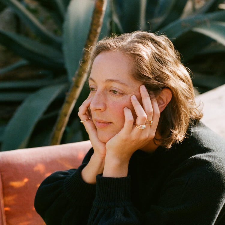 Woman sitting outdoors with plants in the background