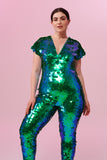 Dark haired model posing in a Rosa Bloom Aphrodite sequin jumpsuit in Emerald green