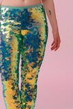 A crop of a womans legs wearing iridescent mint green stretchy sequin Indus leggings covered in large round holographic Rosa Bloom sequins. The sequins glisten, creating a mix of shimmering colours  to create this Chameleon sequin design that looks like it is glowing. 