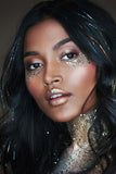 A woman with biodegradable golden mirage coloured body glitter under her eyes, lips and neck