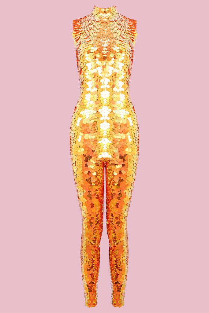 An all-in-one sequin stretchy festival jumpsuit with a high neck, made with large round holographic Rosa Bloom sequins. The Fox jumpsuit in front of a pink background, glistens all over in this colour way, creating a mix of shimmering sequin colours of gold and yellow that sparkles in the light.