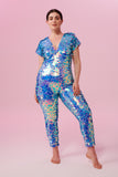 Dark haired model with hair tied back wearing a Rosa Bloom sequin Aphrodite jumpsuit in Amethyst