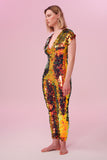 Blonde haired model wearing a Rosa Bloom sequin Aphrodite jumpsuit in Ember