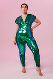 Dark haired model posing in a Rosa Bloom Aphrodite sequin jumpsuit in Emerald green