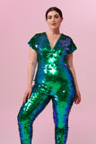 Dark haired model posing in a Rosa Bloom Aphrodite sequin jumpsuit in Emerald green