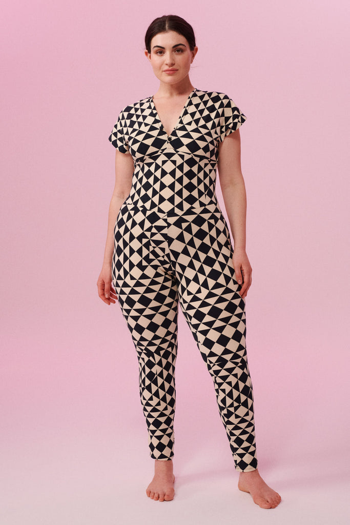 Dark haired model with hair tied back wearing a Geometric black and white tri-print organic cotton jumpsuit