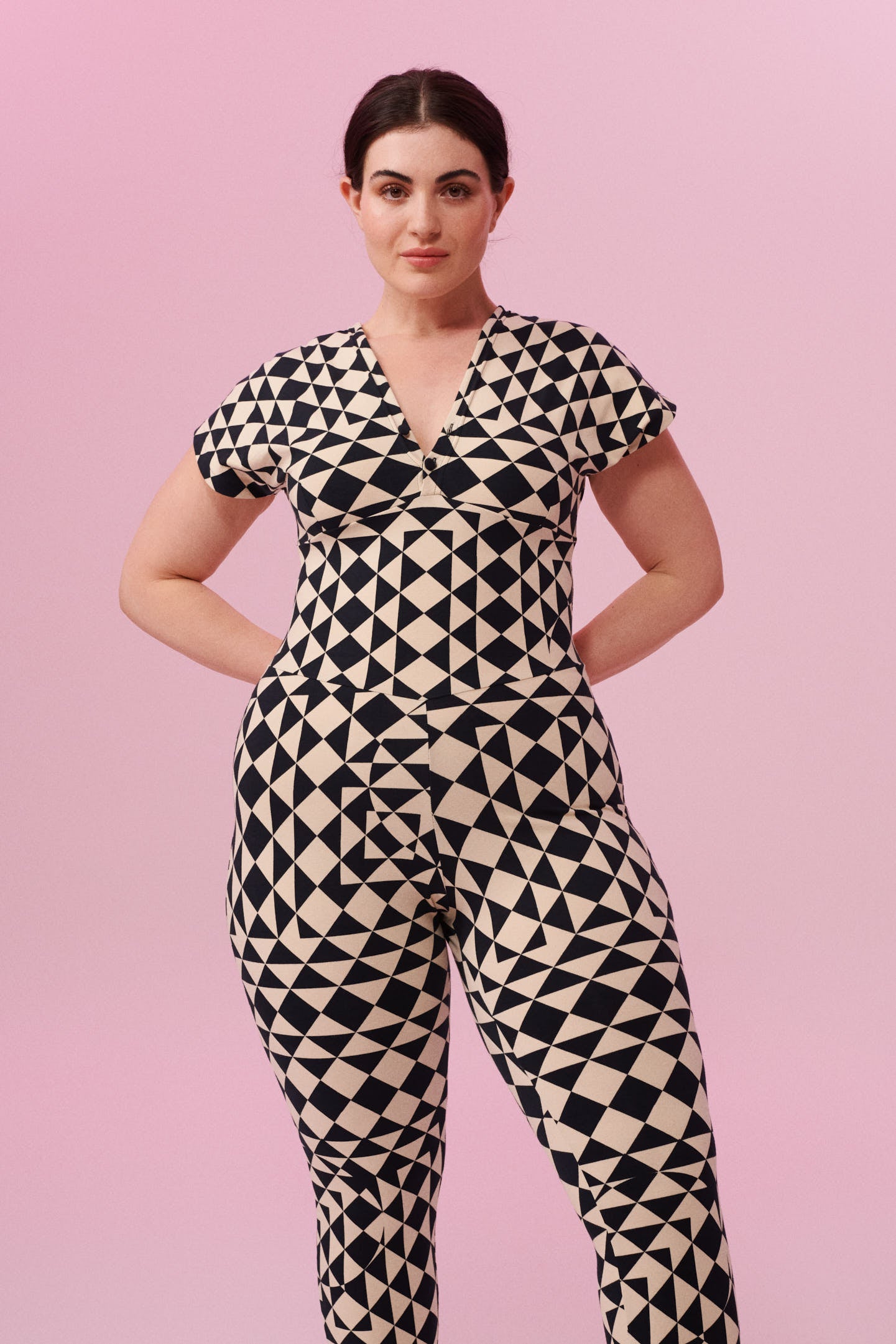 Dark haired model with hair tied back wearing a Geometric black and white tri-print organic cotton jumpsuit