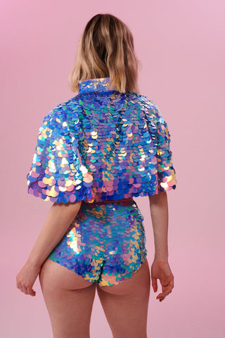 Rear view of a woman wearing Rosa Bloom Shimmering Sequin Cape with pink blue and purple sequins