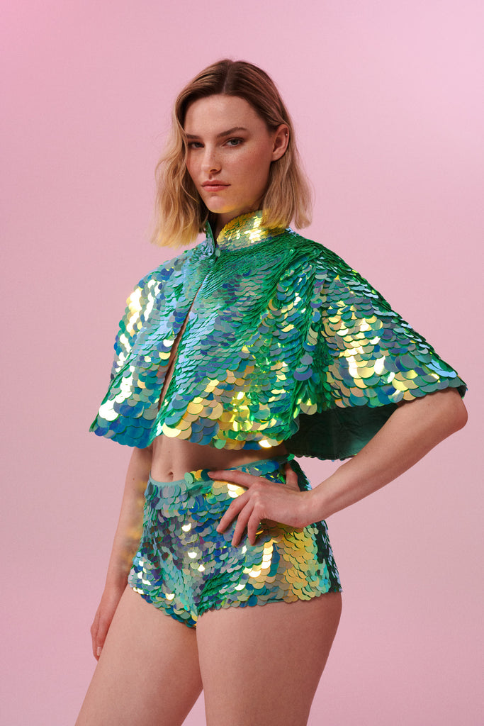 Side view of a woman wearing Rosa Bloom Shimmering Sequin Cape with light green sequins
