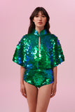 Front view of a woman wearing Rosa Bloom Shimmering Sequin Cape with Emerald green sequins