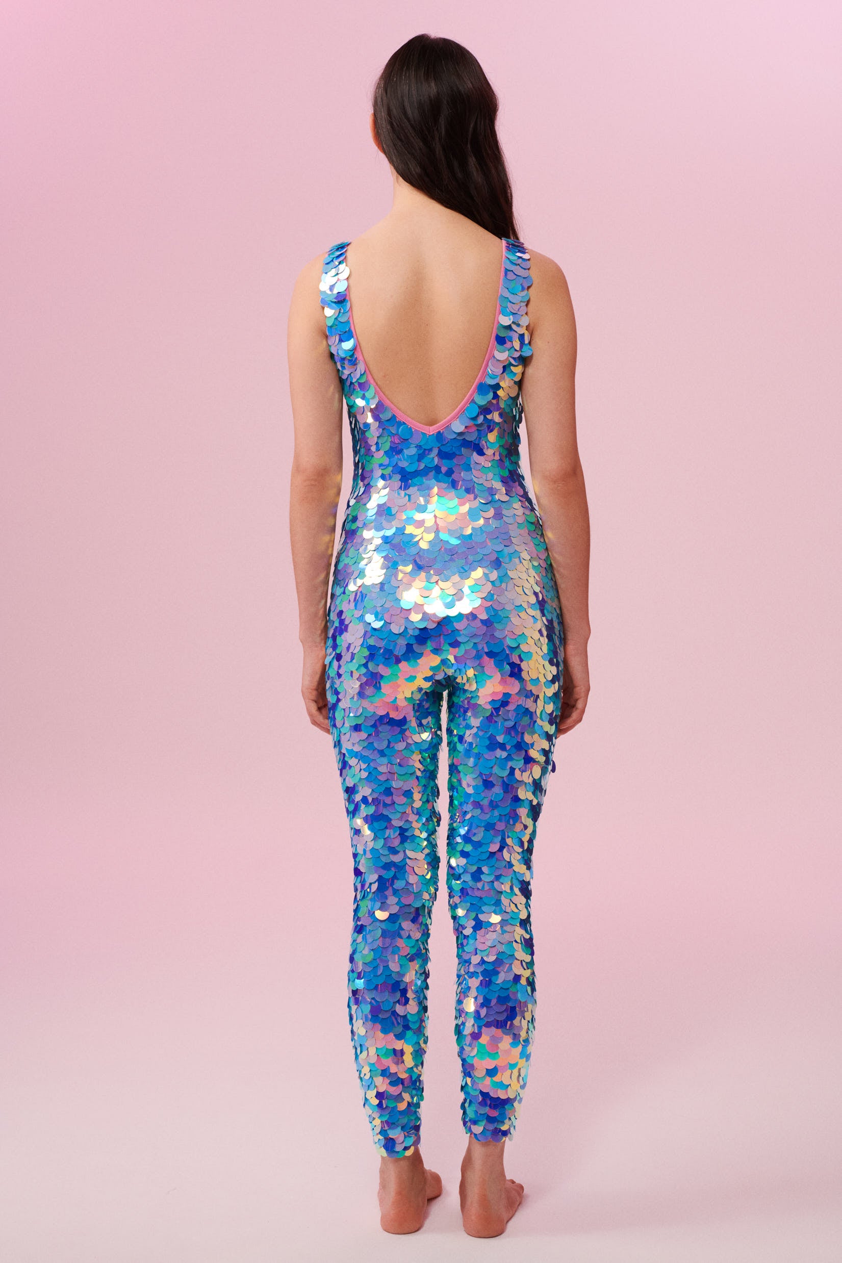 Rear view of a woman wearing blue and pink sequin Rosa Bloom jumpsuit
