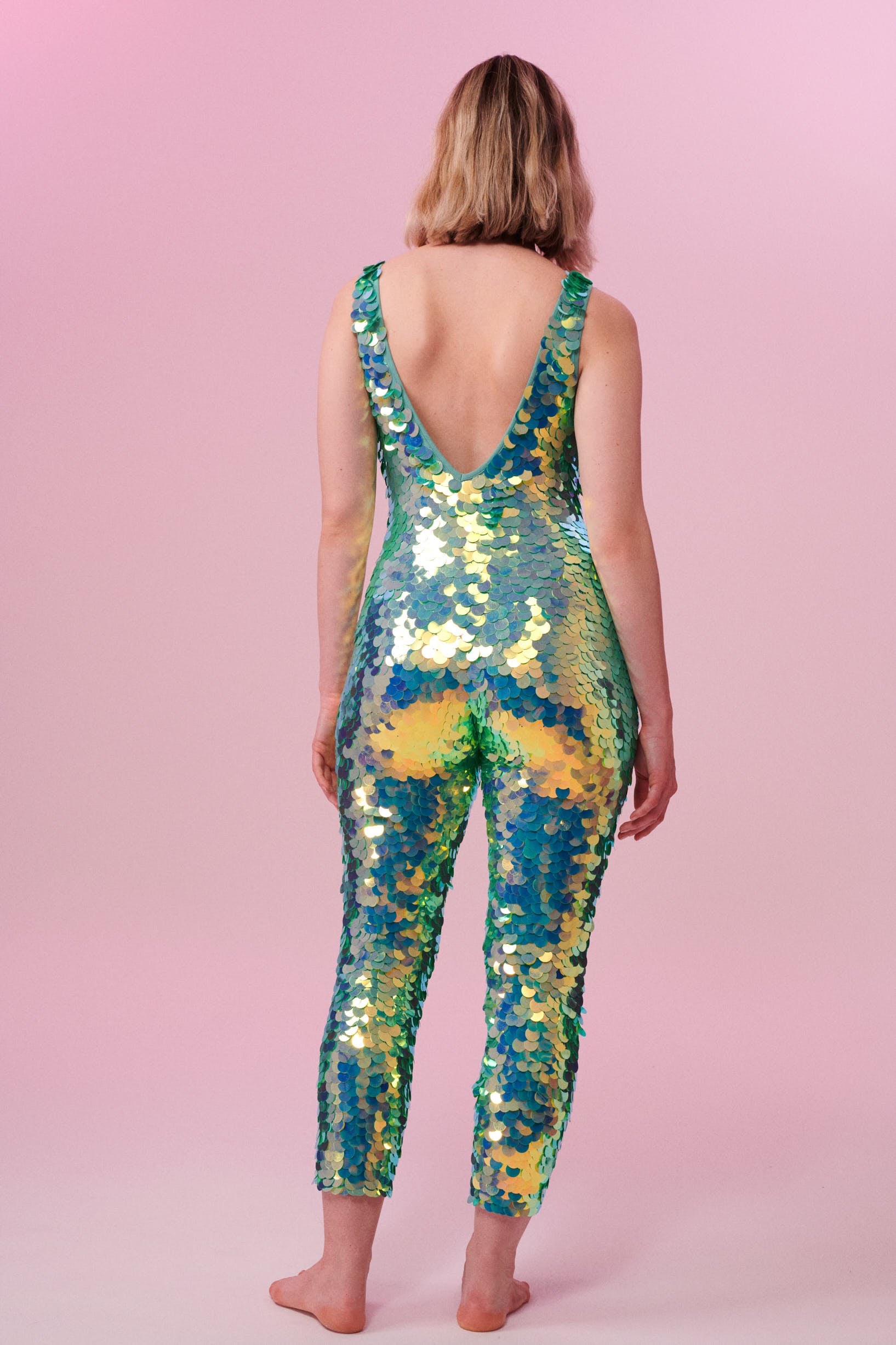 Rear view of a woman wearing a green sequin Rosa Bloom jumpsuit