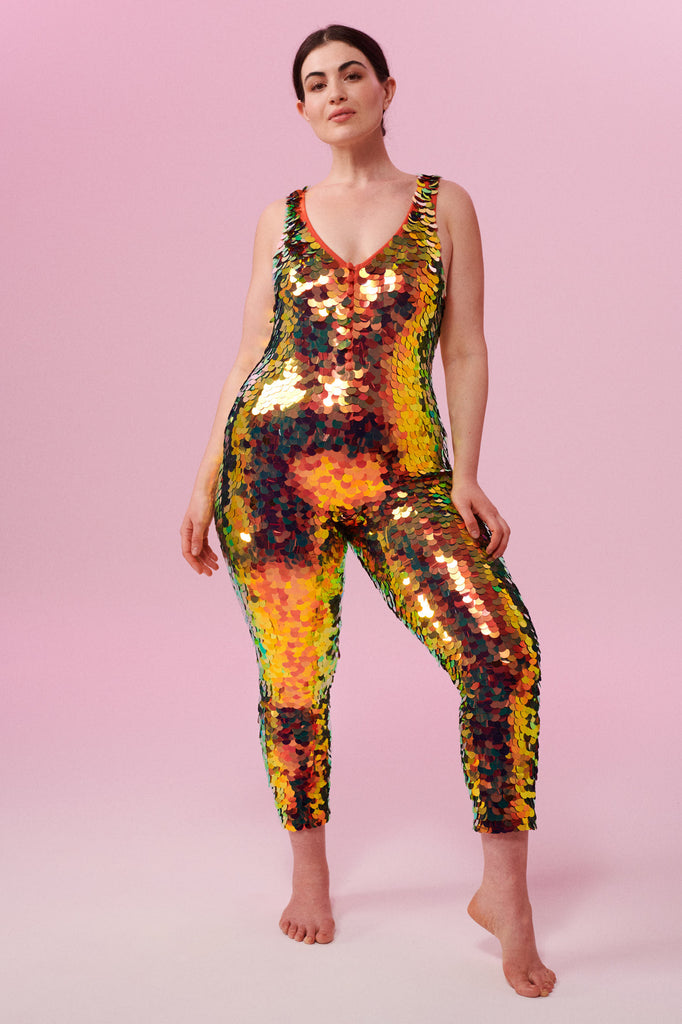 Front view of a woman wearing a red and gold sequin Rosa Bloom jumpsuit
