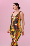 Side view of a woman wearing a red and gold sequin Rosa Bloom jumpsuit