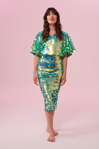 Front view of a dark haired woman wearing a Rosa Bloom green sequin mid length sequin tube skirt