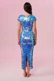 A woman standing with her back to the viewer wearing a blue and pink Amethyst,  figure hugging  long sequin dress with small capped sleeves covered completely in large round holographic Rosa Bloom sequins. The sequin colours are a mix of soft rose pink, lilac, and cornflower blue. 