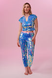 A woman wearing iridescent pink, purple and blue, stretchy sequin Indus leggings covered in large round holographic Rosa Bloom sequins. The model is also wearing a matching stretchy sequin top, in matching colours. The sequins glisten, creating a mix of shimmering colours  to create this Amethyst sequin design that looks like it is glowing. 