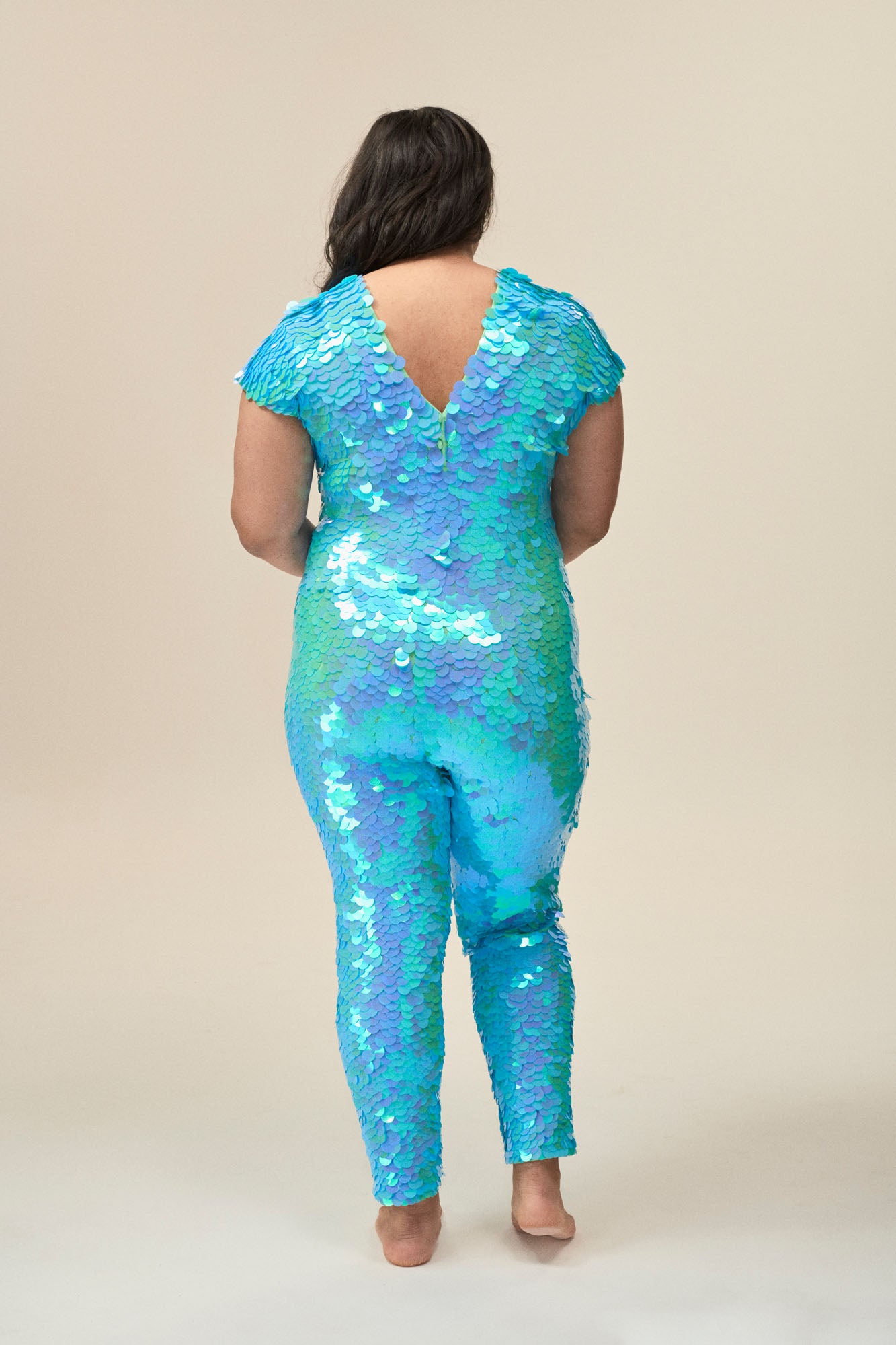 Back view of a woman wearing the Rosa Bloom Aphrodite jumpsuit embellished in hand sewn sparkly aqua blue sequins.
