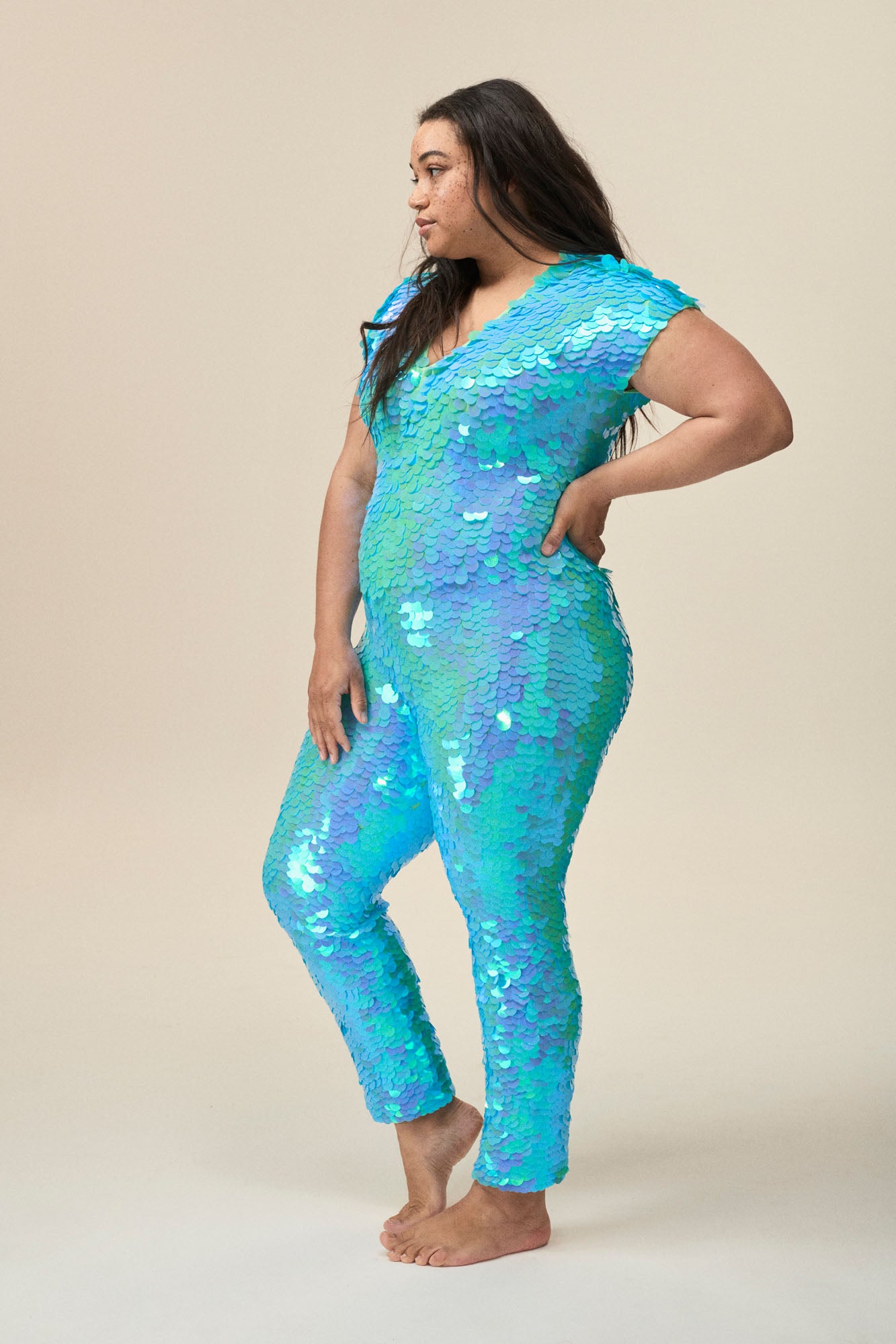 Side view of a woman wearing the Rosa Bloom Aphrodite jumpsuit embellished in hand sewn sparkly aqua blue sequins.