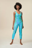 Front view of a woman wearing the Rosa Bloom Electra jumpsuit in a mesmerising aqua blue. A stretchy jumpsuit with button fronted detail that hugs and contours her body embellishing her in sparkling sequins.