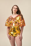 Front view of a woman wearing Rosa Bloom Stretchy Gigi hotpants in large sparkling orange sequins