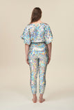 A rear view of a woman wearing a silver sequin top with large cape sleeves covered in large round holographic silver sequins.