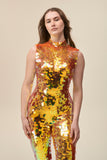 A close up shot of a woman wearing a bright orange sequin jumpsuit with a high neck. 