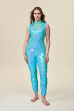 A full body view of a woman wearing a bright aqua blue sequin jumpsuit with a high neck.