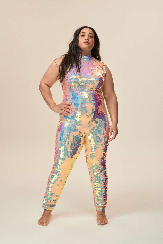 A woman wears a high neck plus-sized sequin jumpsuit covered in large round off-white sequins. 