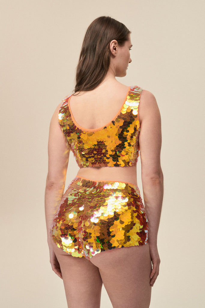 Rear view of a woman wearing stretchy Rosa Bloom Gigi hotpants with large sparkling orange sequins 